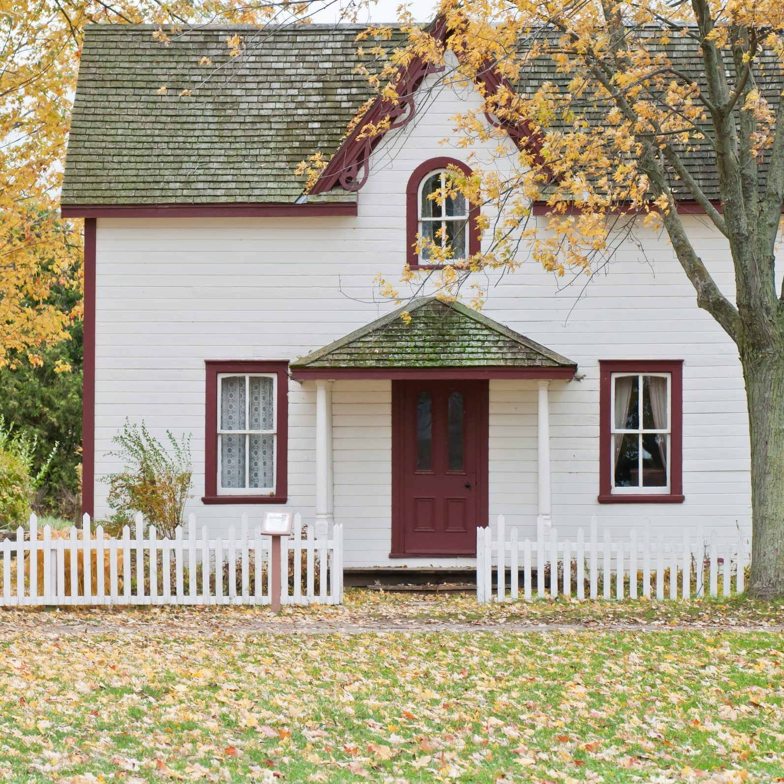 Photo of a modest house with leaves on the lawn 