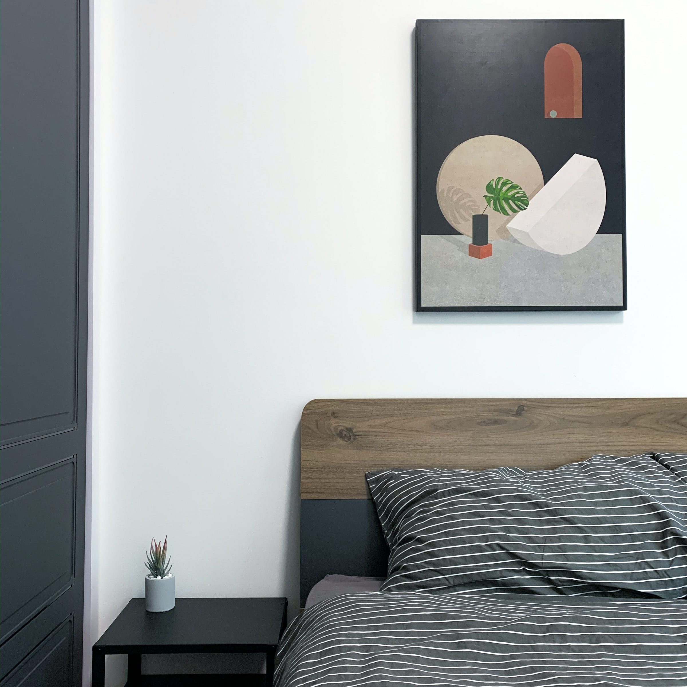 Image of a modern bedroom with a bed coffee table and a piece of art on the wall 